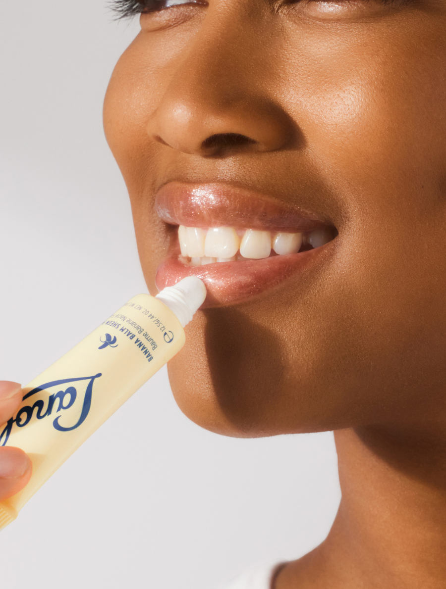 Close up shot of model applying the Lanolips Banana Balm Lip Sheen 3-in-1