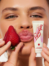Model holding Lanolips Lip Scrub Strawberry and with the mixture of ultra-pure grade lanolin, finely ground strawberry seeds and sugar, it leaves your lips deeply hydrated.