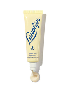 Lanolips Banana Balm Sheen 3-in-1 in a soft yellow squeezable tube with a white cap. The packaging features the Lanolips logo in bold blue lettering and a small banana icon, highlighting its creamy, nourishing formula. A swirl of the balm is visible at the opening, showcasing its rich texture and subtle pearlescent sheen. This hydrating lip balm is infused with lanolin and banana extract, designed to soften, condition, and add a natural glow to dry lips.