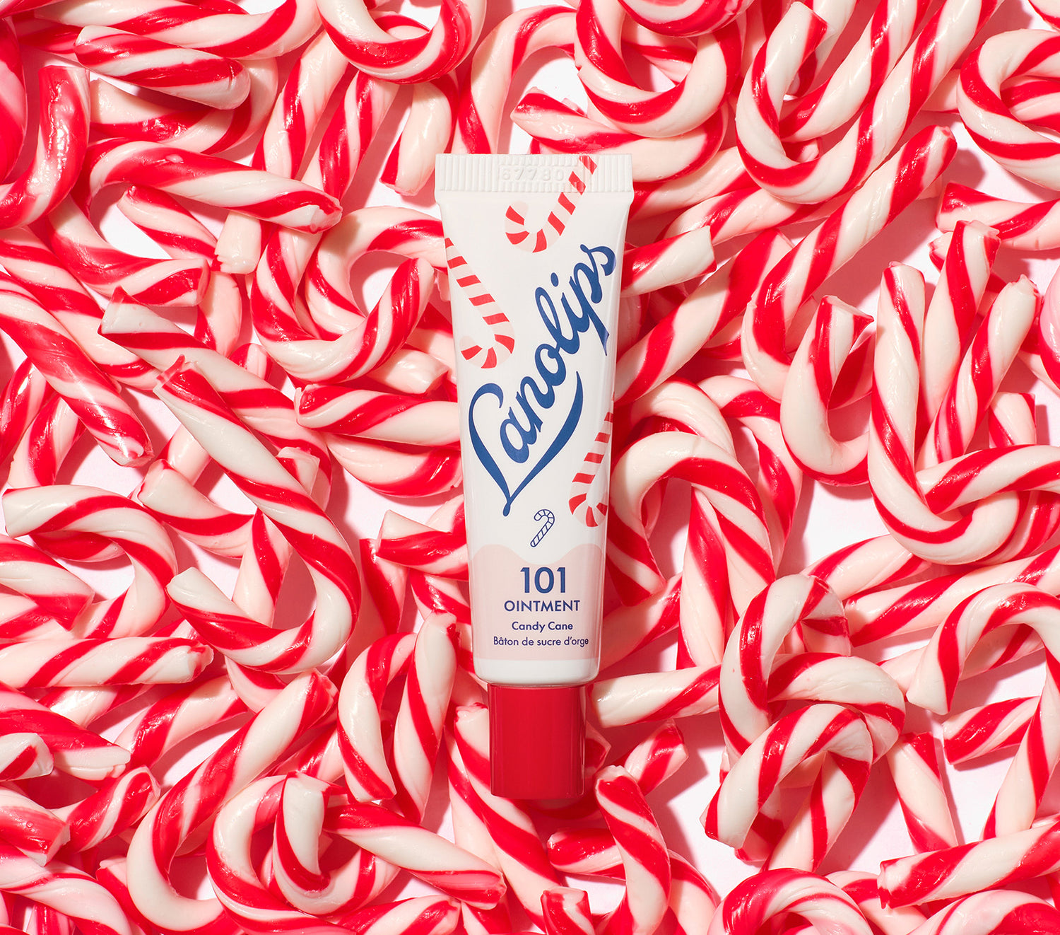 Lanolips 101 Ointment Multi-Balm Candy Cane tube surrounded by red and white candy canes. Limited edition festive flavours. 