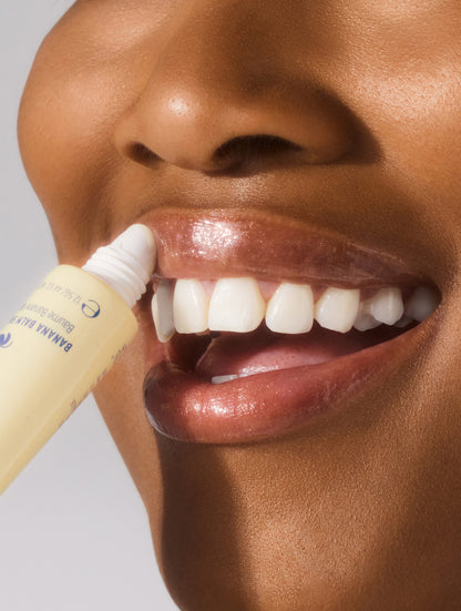 Close-up shot of model applying Lanolips Banana Balm Lip Sheen 3-in-1