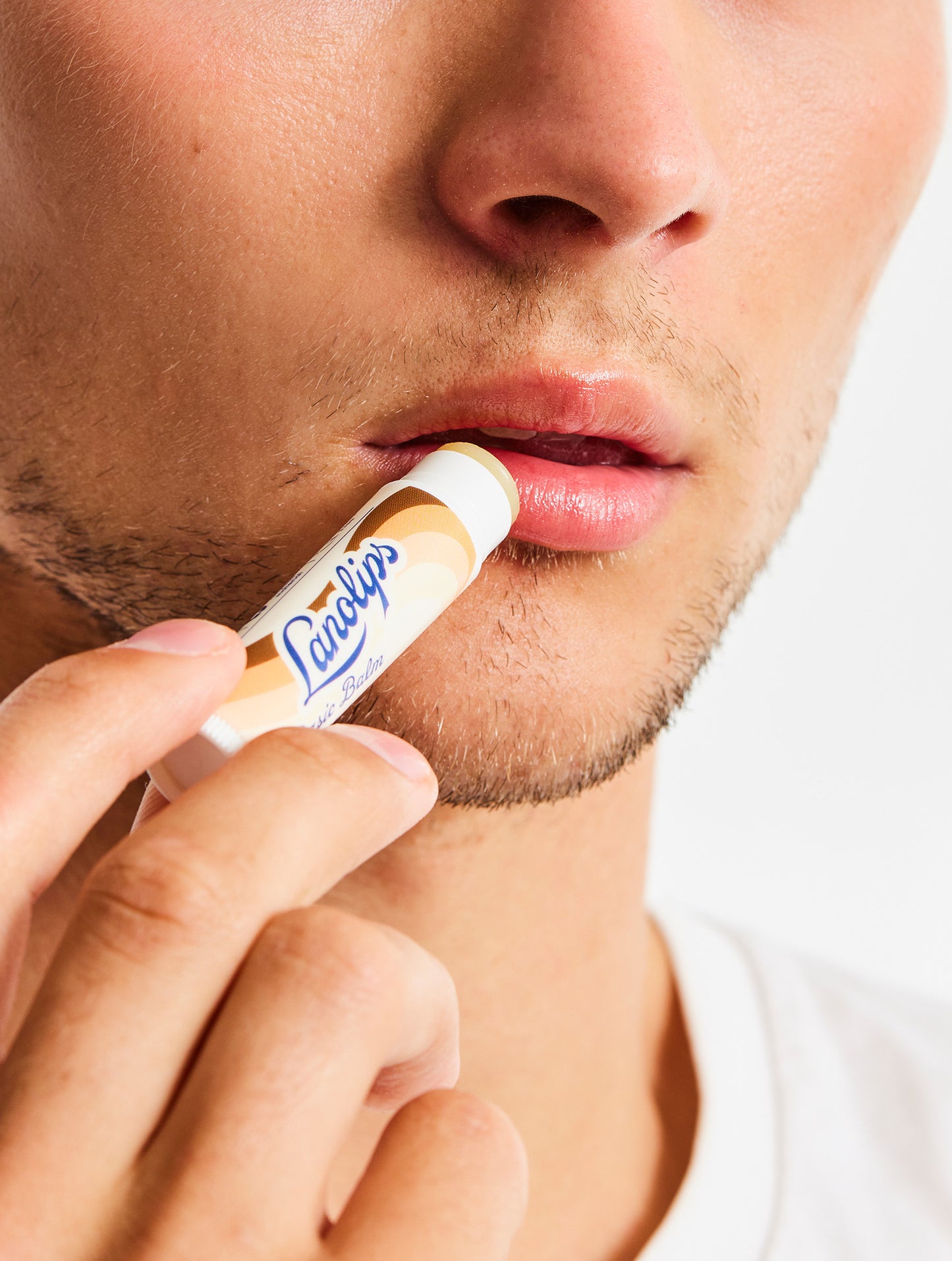 Model applying Lanolips Basic Balm Coconutter onto their lips.