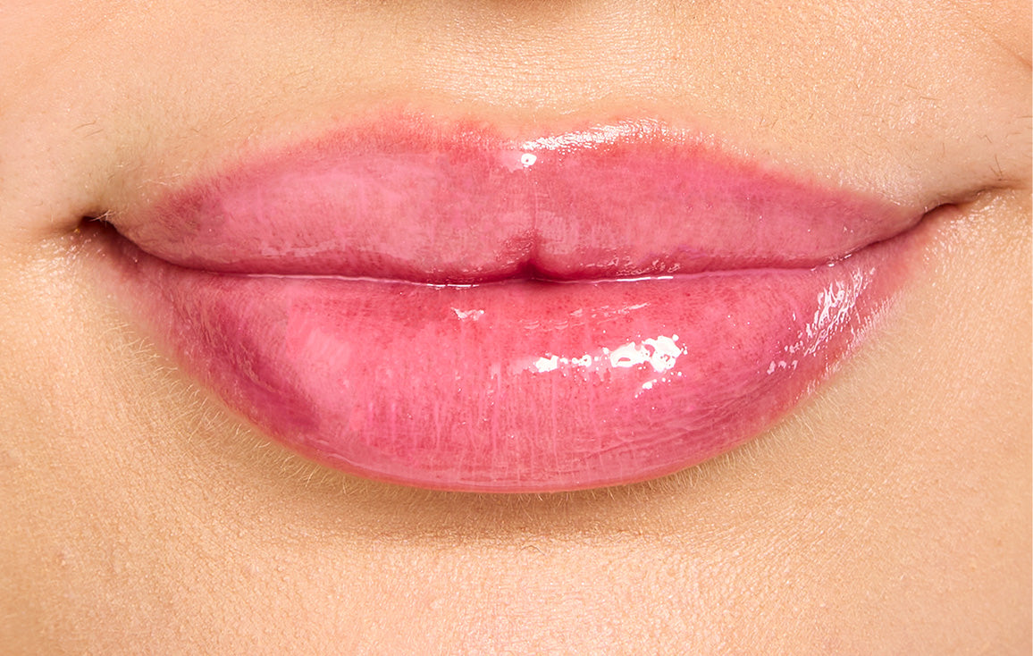 Close-up of model's lips after applying Lanolips Hyaluronic Lip Oil in Raspberry. Infused with all-natural lanolin, vitamin e, and hyaluronic acid, this lip oil deeply hydrates while adding a natural, fruity pink flush for soft, plump, and vibrant lips.